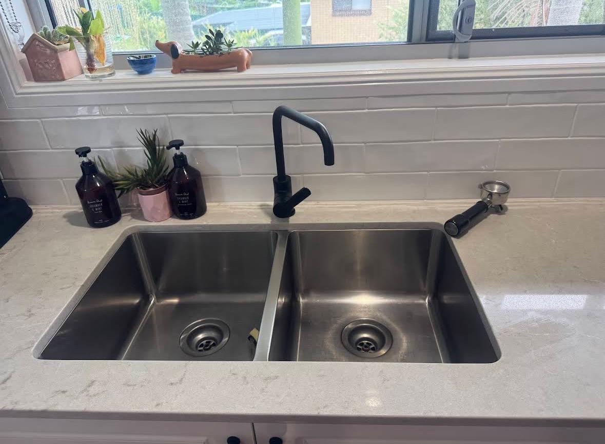 Meticulously cleaned stainless steel kitchen sink and faucet in a modern home
